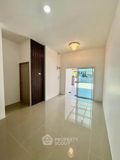 Spacious modern living room with elegant chandelier and sliding glass doors leading to patio.