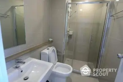 Modern bathroom with glass shower enclosure, white fixtures, and large mirror creating a clean, minimalist aesthetic perfect for urban living.