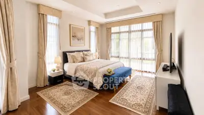 Luxurious bedroom with elegant decor, large windows, and hardwood floors in a modern home.