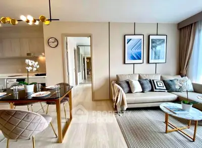 Modern living room with stylish decor and open kitchen layout, featuring elegant furniture and natural light.