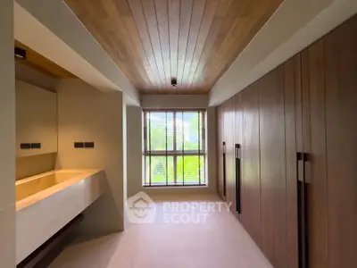 Luxurious bathroom with wooden accents and large window offering serene garden view.