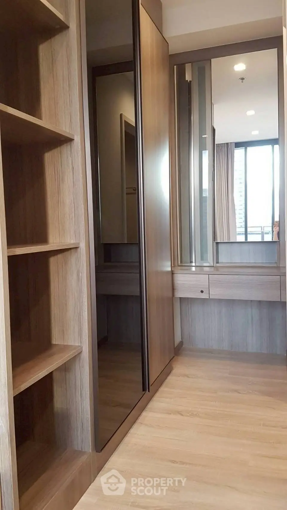 Spacious walk-in closet with wooden shelves and mirrored doors in modern apartment.