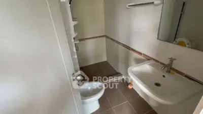 Compact bathroom with modern sink and toilet, featuring neutral tiles.
