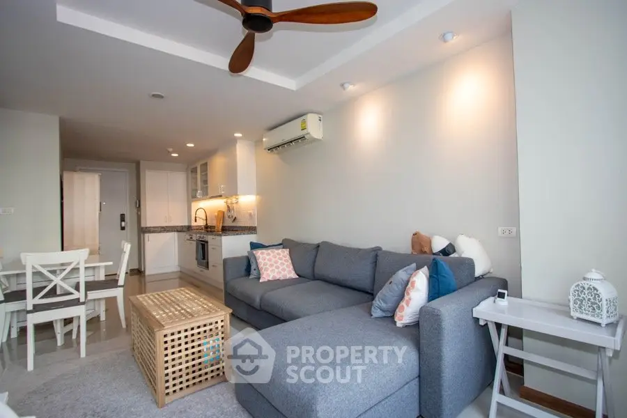Modern living room with cozy gray sofa and stylish decor in open layout apartment.