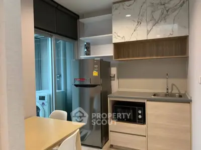Modern kitchen with sleek appliances and marble accents in a compact layout.