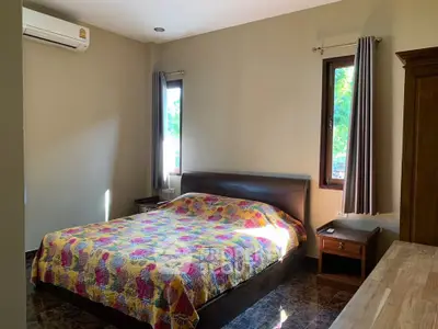 Cozy bedroom with colorful quilt, natural light, and modern furnishings.