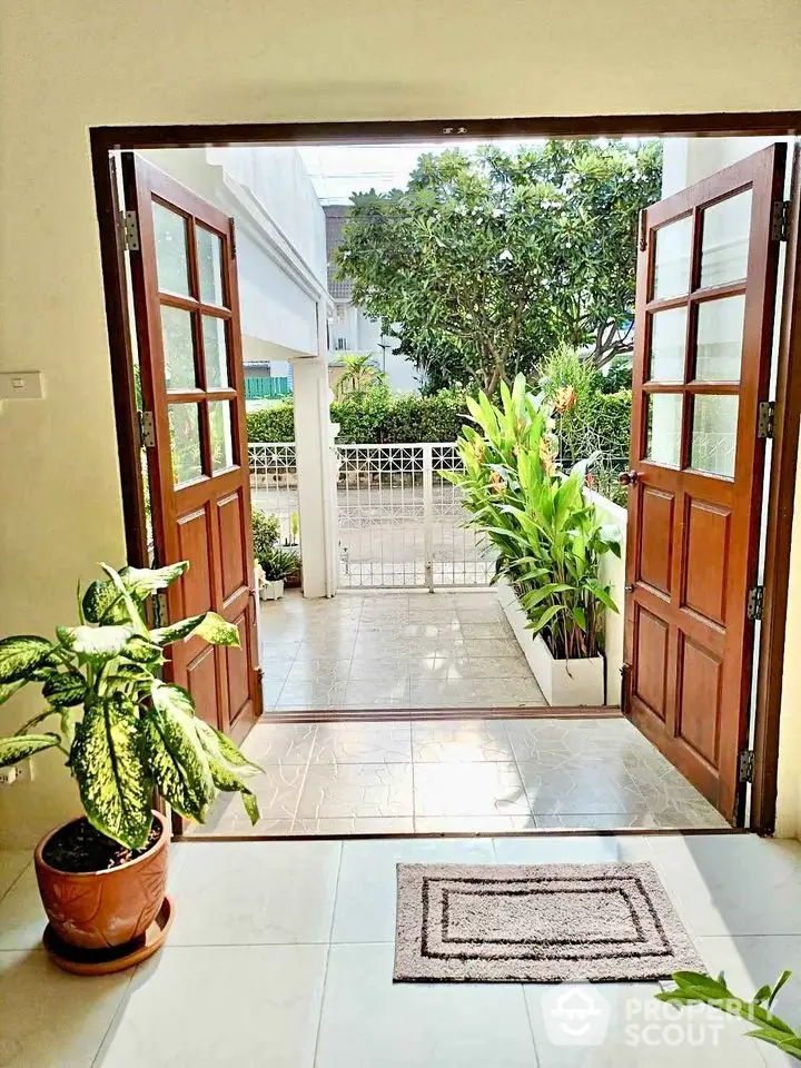 Inviting entrance with double doors opening to a lush garden view, perfect for serene living.