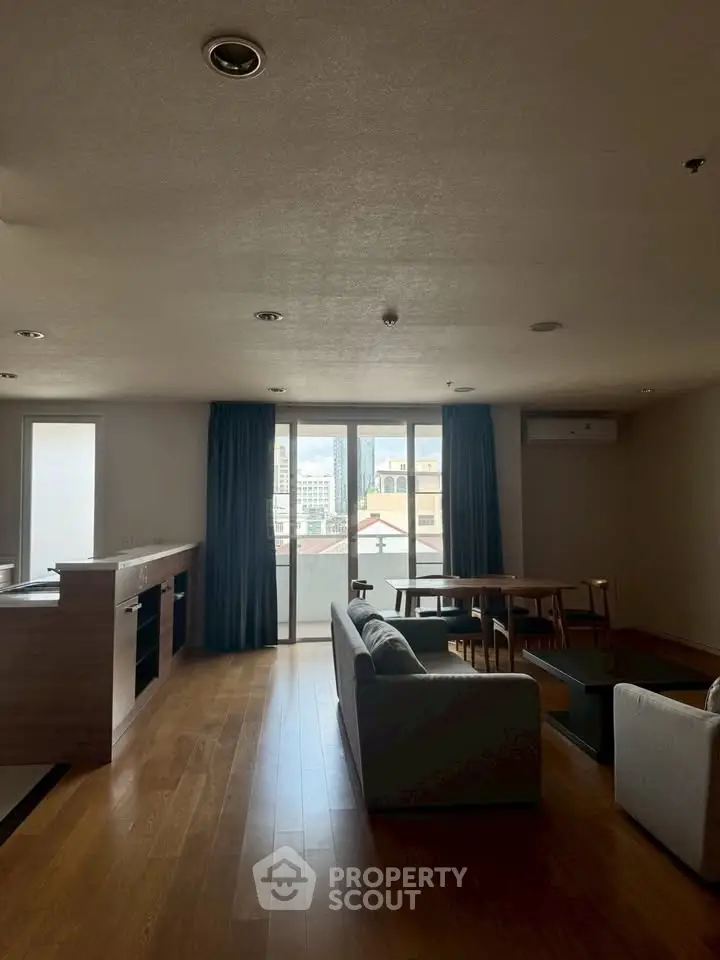 Spacious living room with modern furniture and city view through large windows.