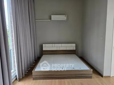 Modern bedroom with minimalist bed frame and air conditioning, featuring floor-to-ceiling curtains.