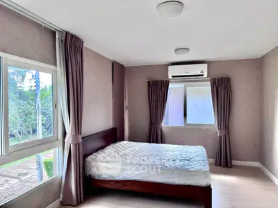 Spacious bedroom with large windows and air conditioning, offering a serene view.