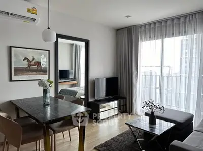 Modern living room with dining area and balcony view, featuring sleek furniture and elegant decor.