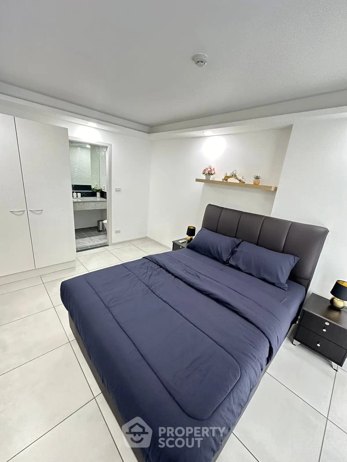 Modern bedroom with sleek design and ensuite bathroom, featuring a comfortable bed and stylish decor.