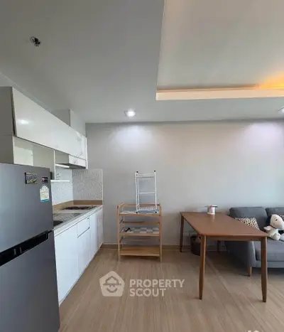 Modern kitchen with sleek white cabinets and cozy dining area in open layout apartment.