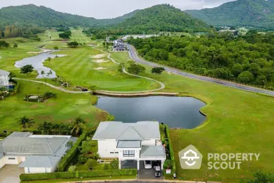 Stunning aerial view of luxury home by golf course with lush greenery and scenic mountains.