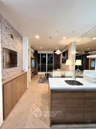 Modern open-layout kitchen with stylish living area and balcony view, featuring sleek design and contemporary lighting.