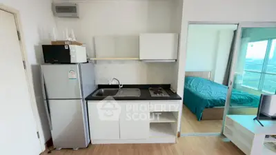 Modern compact kitchen with adjacent bedroom in a bright apartment