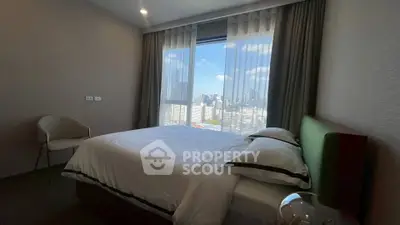 Modern bedroom with city view, featuring elegant decor and large window for natural light.