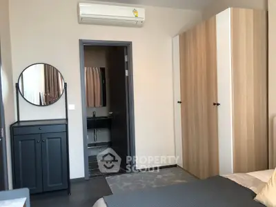 Modern bedroom with stylish wardrobe and ensuite bathroom in a contemporary apartment.