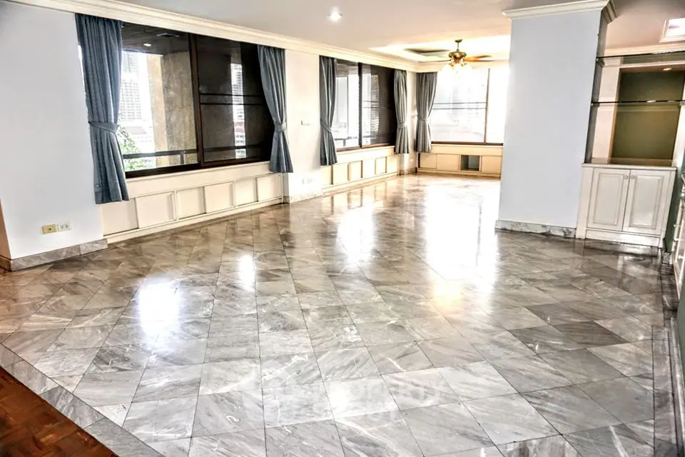 Spacious living room with marble flooring and large windows in a modern apartment.