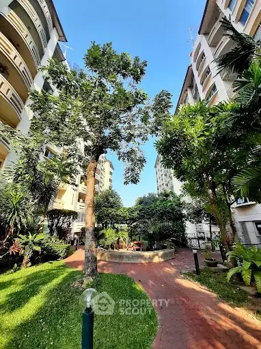 Beautiful garden courtyard between modern apartment buildings with lush greenery.