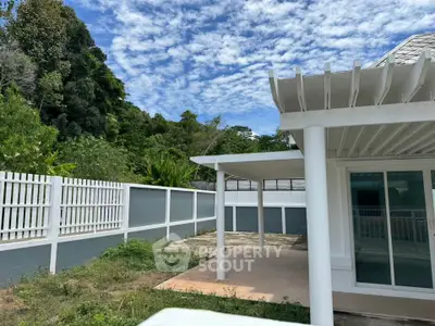 Charming outdoor patio with lush greenery and modern white pergola, perfect for relaxation and entertaining.