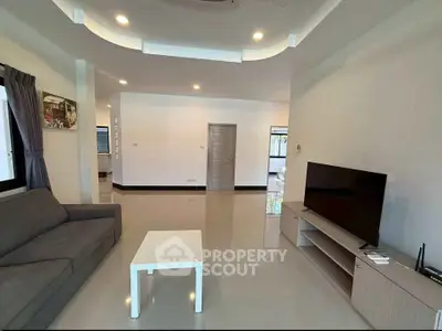 Spacious modern living room with sleek design and natural light, featuring a comfortable sofa and flat-screen TV.