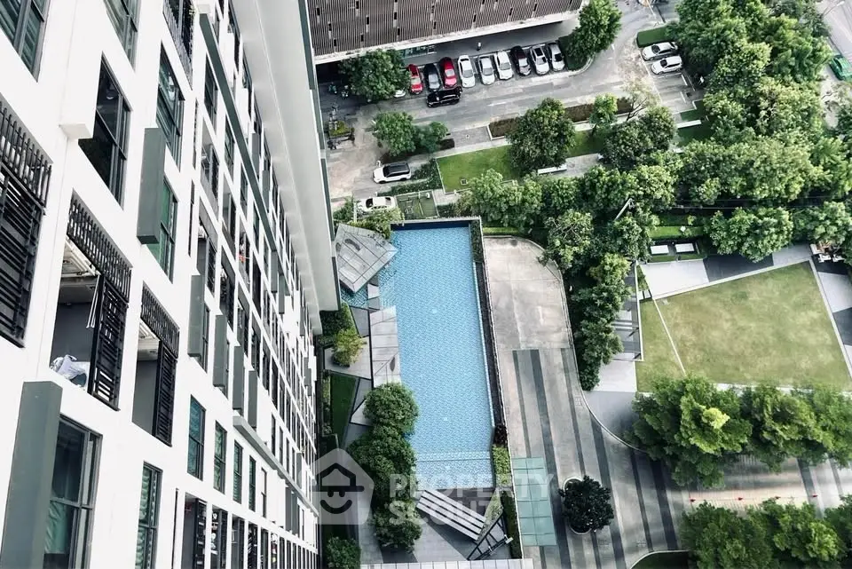 Stunning aerial view of modern apartment building with pool and lush garden