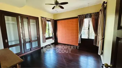 Spacious bedroom with dark wood flooring and elegant curtains
