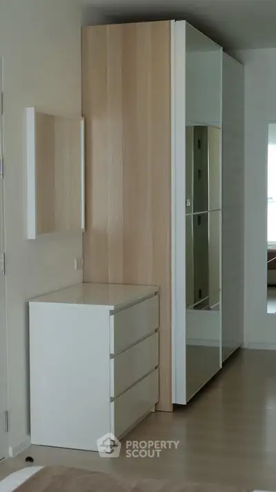 Modern bedroom with sleek wardrobe and dresser in a stylish apartment.
