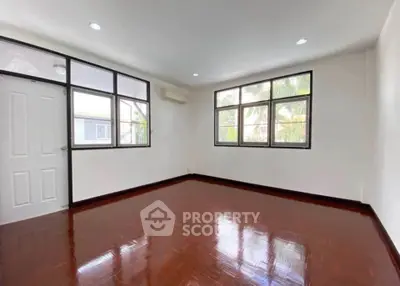 Spacious empty room with large windows and polished wooden floors