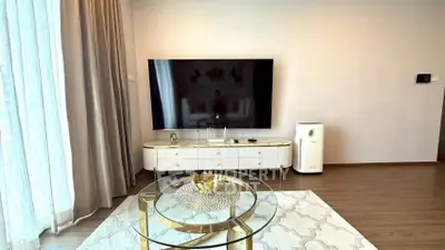 Modern living room with large TV, elegant furniture, and stylish decor