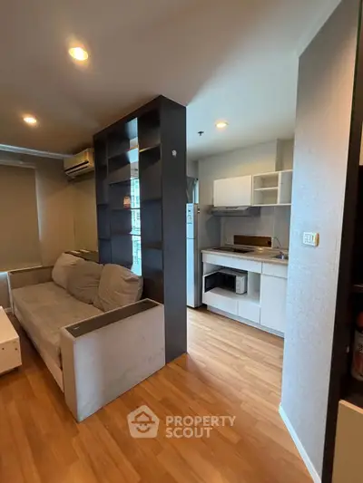Modern open-plan living room with cozy sofa and sleek kitchen area in stylish apartment.