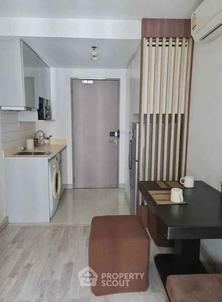 Modern compact kitchen with washing machine and dining area in stylish apartment.