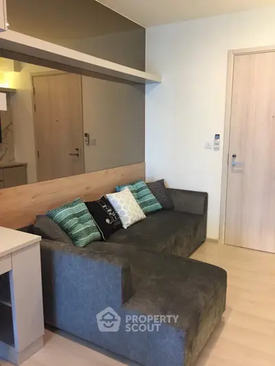 Modern living room with stylish gray sofa and decorative pillows in a cozy apartment setting.