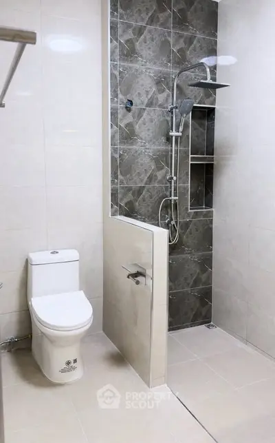 Modern bathroom with sleek shower and toilet in elegant tile design.