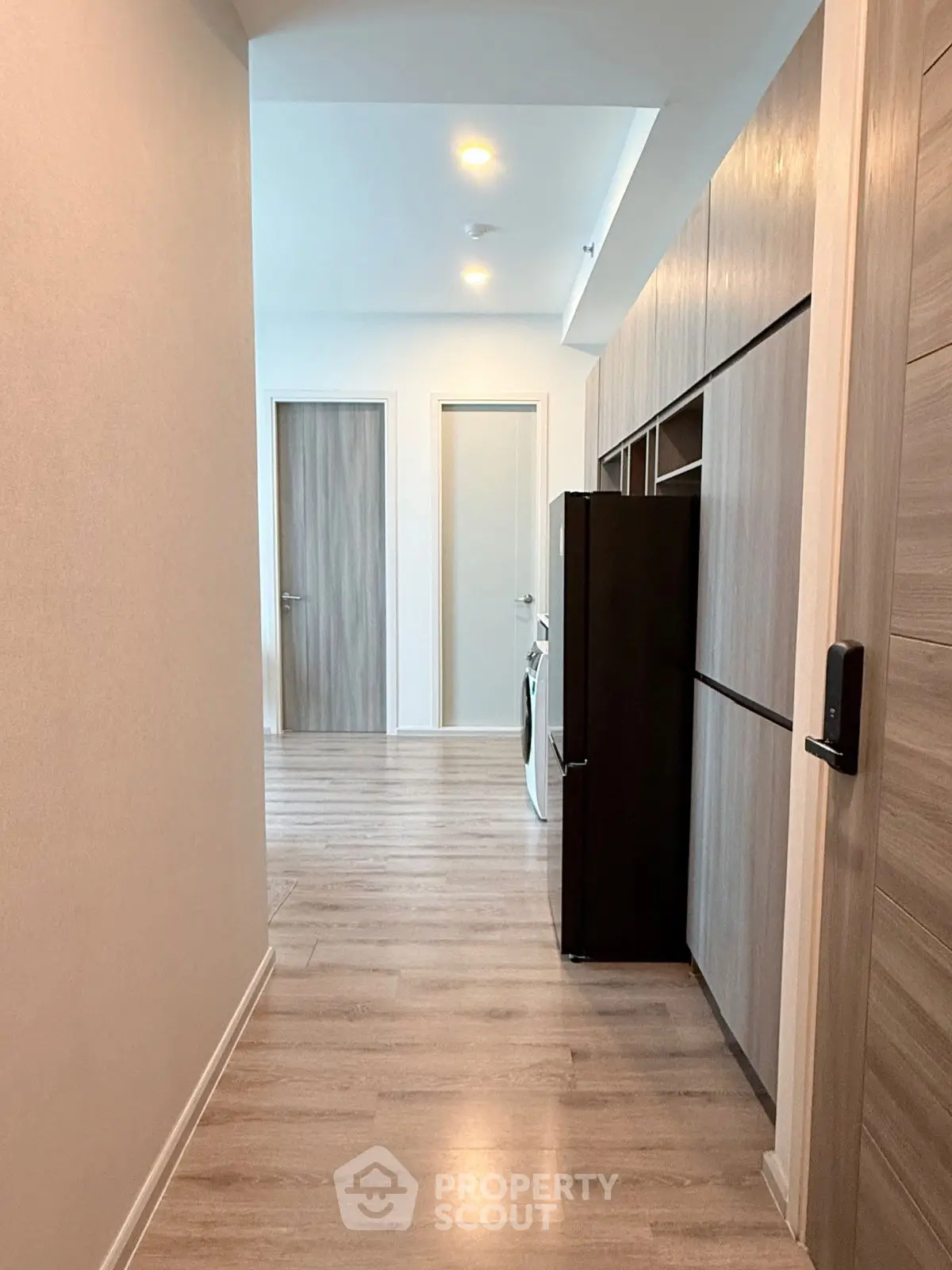 Modern hallway with sleek wooden flooring and built-in storage cabinets.