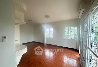 Spacious empty living room with wooden flooring and large windows in a modern home.