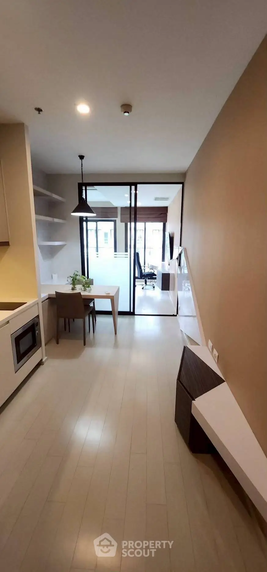 Modern open-plan apartment with sleek kitchen and cozy dining area, featuring floor-to-ceiling windows for natural light.