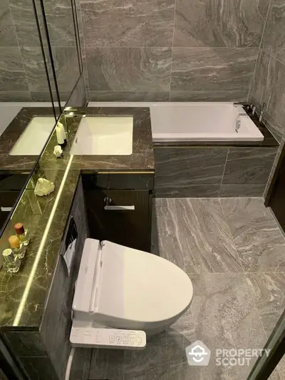 Modern bathroom with sleek marble tiles, featuring a high-tech toilet, spacious bathtub, and a well-lit vanity area for a luxurious living experience.