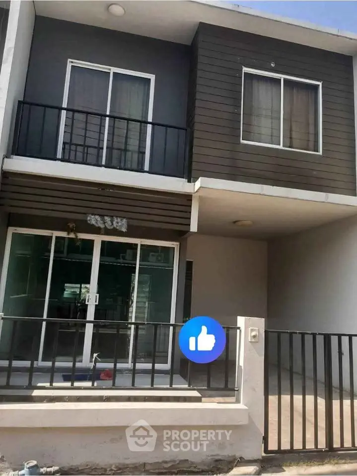 Modern two-story house with balcony and large windows, perfect for family living.