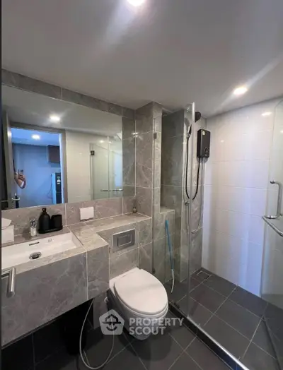 Modern bathroom with sleek design, featuring a glass shower enclosure and elegant fixtures.