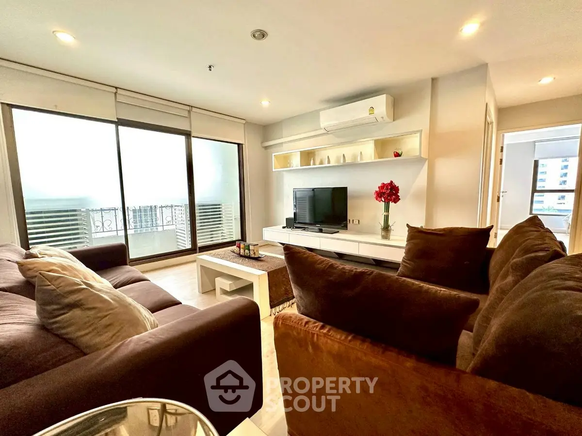 Spacious living room with modern decor and large windows leading to a balcony.
