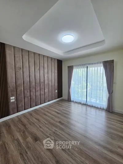 Spacious empty room with elegant wood flooring and large window with curtains, perfect for customization.