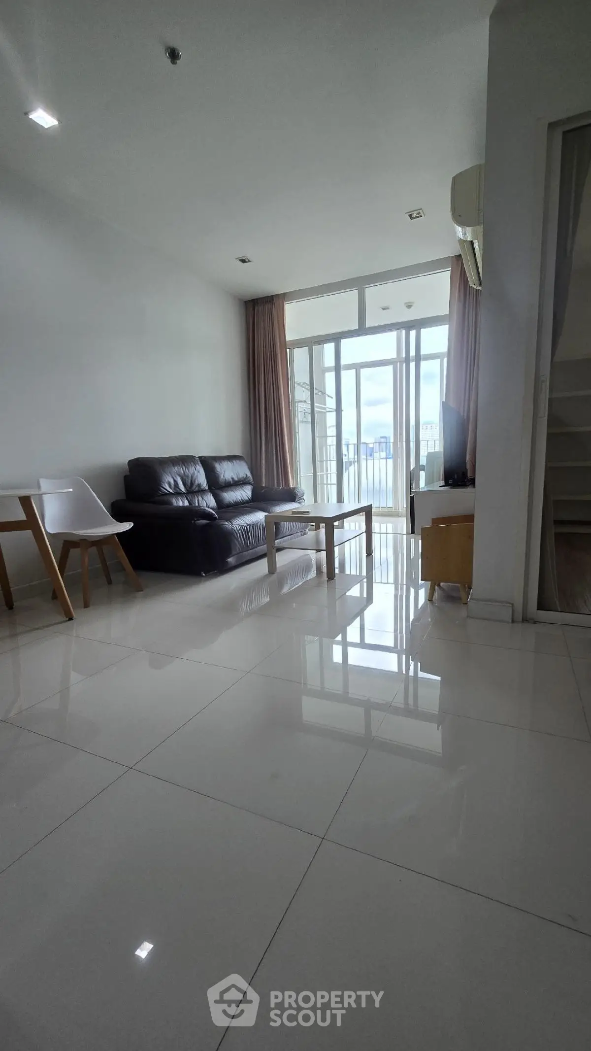 Spacious modern living room with sleek furniture and large windows offering natural light and city views.
