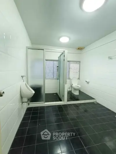 Spacious bathroom with modern fixtures and sleek black tile flooring.