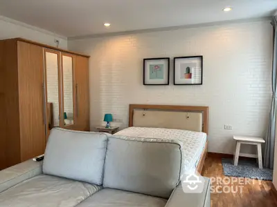 Cozy bedroom with a comfortable queen-sized bed, modern furnishings, and a chic white brick wall, perfect for restful nights and stylish living.