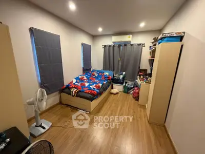 Cozy bedroom with wooden flooring and colorful bedding, perfect for relaxation.