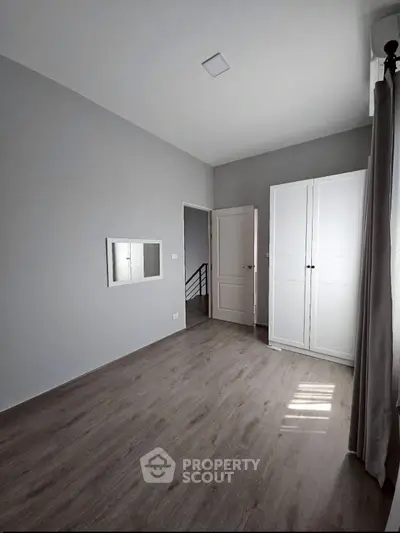 Minimalist bedroom with wooden flooring and white wardrobe