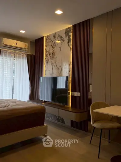 Modern bedroom with stylish decor, featuring a mounted TV and elegant lighting, perfect for urban living.