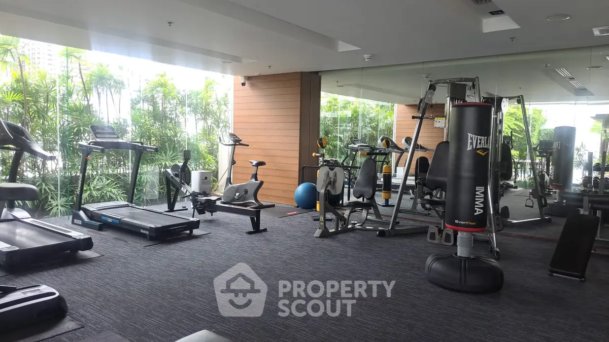 Modern gym with state-of-the-art equipment and lush greenery view, perfect for fitness enthusiasts.